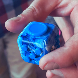 Blue fidget cube with different buttons and textures.