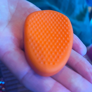 Orange textured fidget stone held in a person’s hand.
